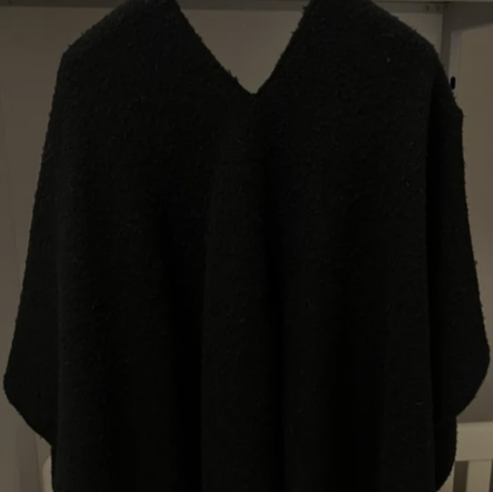 Poncho cape with central opening for the head and wider opening on one shoulder.